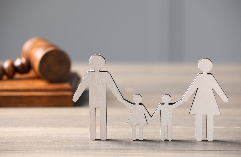 Figure of parents with children and gavel on wooden table