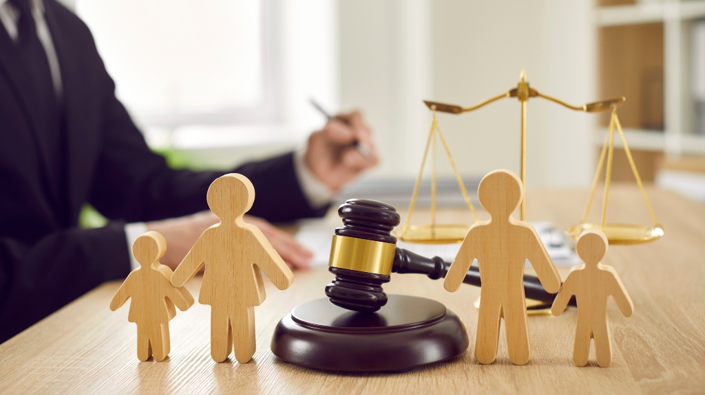 Gavel, sound block and little wooden figures of parents and children placed on desk