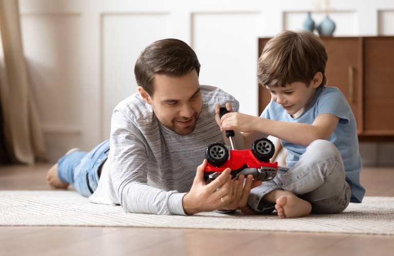 father and son play with toy car